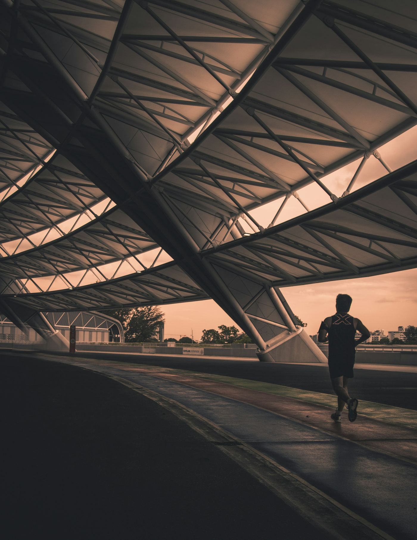 A runner beneath a steel canopy at dusk